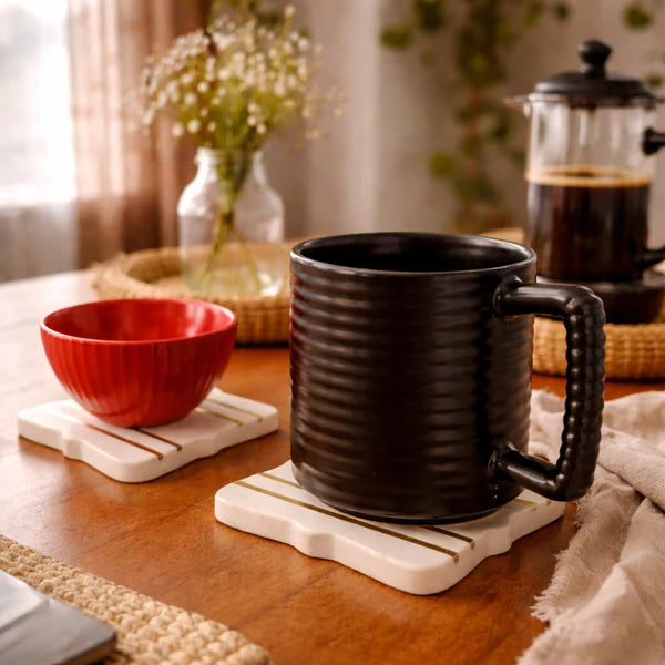 Black mug and red bowl on a wooden table with a blurred background