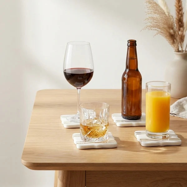 Bracket Luxe Marble Coasters with gold stripe accents holding wine glass, whiskey glass and juice on wooden table