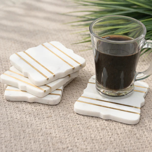 Bracket Luxe Marble Coasters with gold stripe accents holding glass coffee cup beside stacked coasters