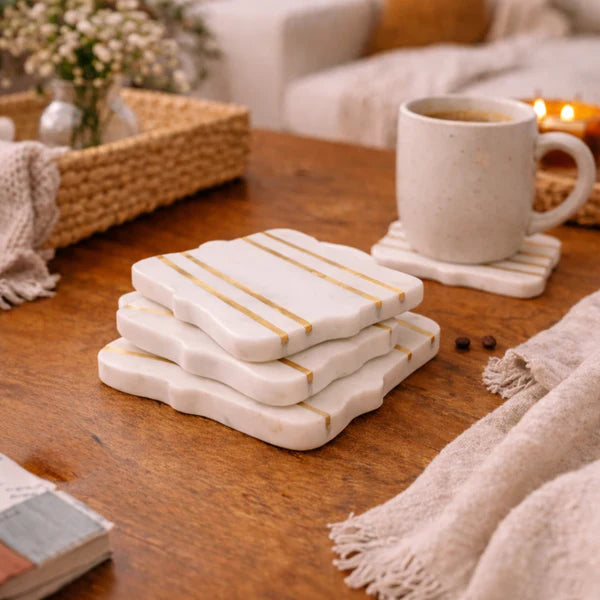 Stack of Bracket Luxe Marble Coasters with gold stripe accents on wooden coffee table with coffee mug