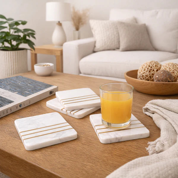 Set of marble coasters with gold stripes on a wooden table in a cozy living room.