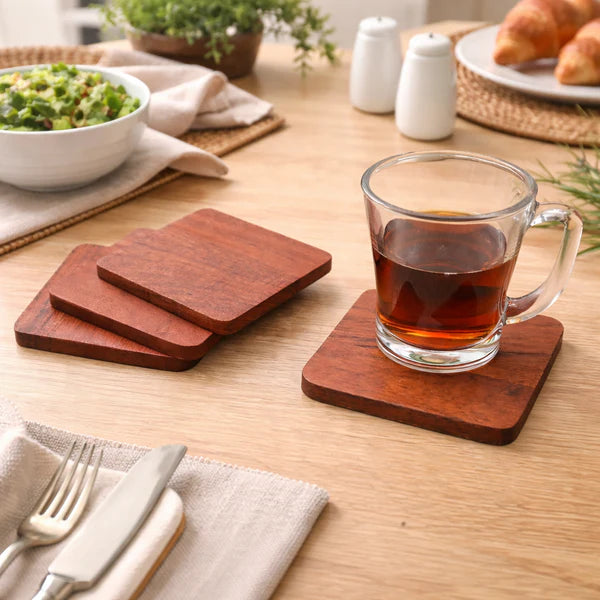 Terra Square Wooden coasters on a table with a glass of tea and a plate of food.