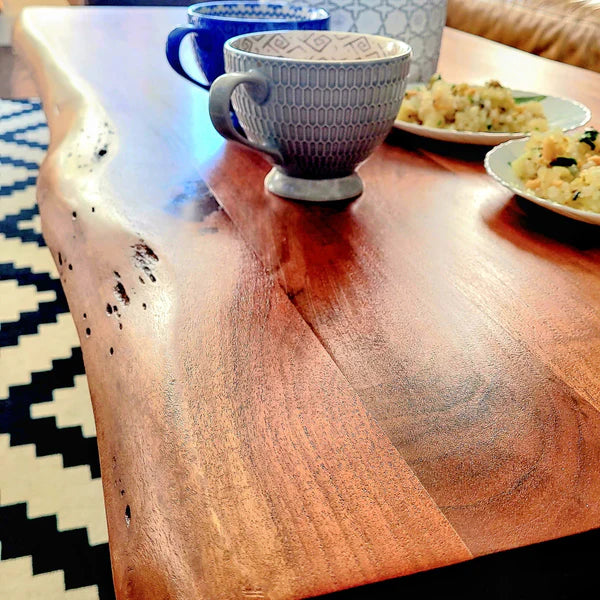 Natural live edge detail of solid acacia wood coffee table with raw edges