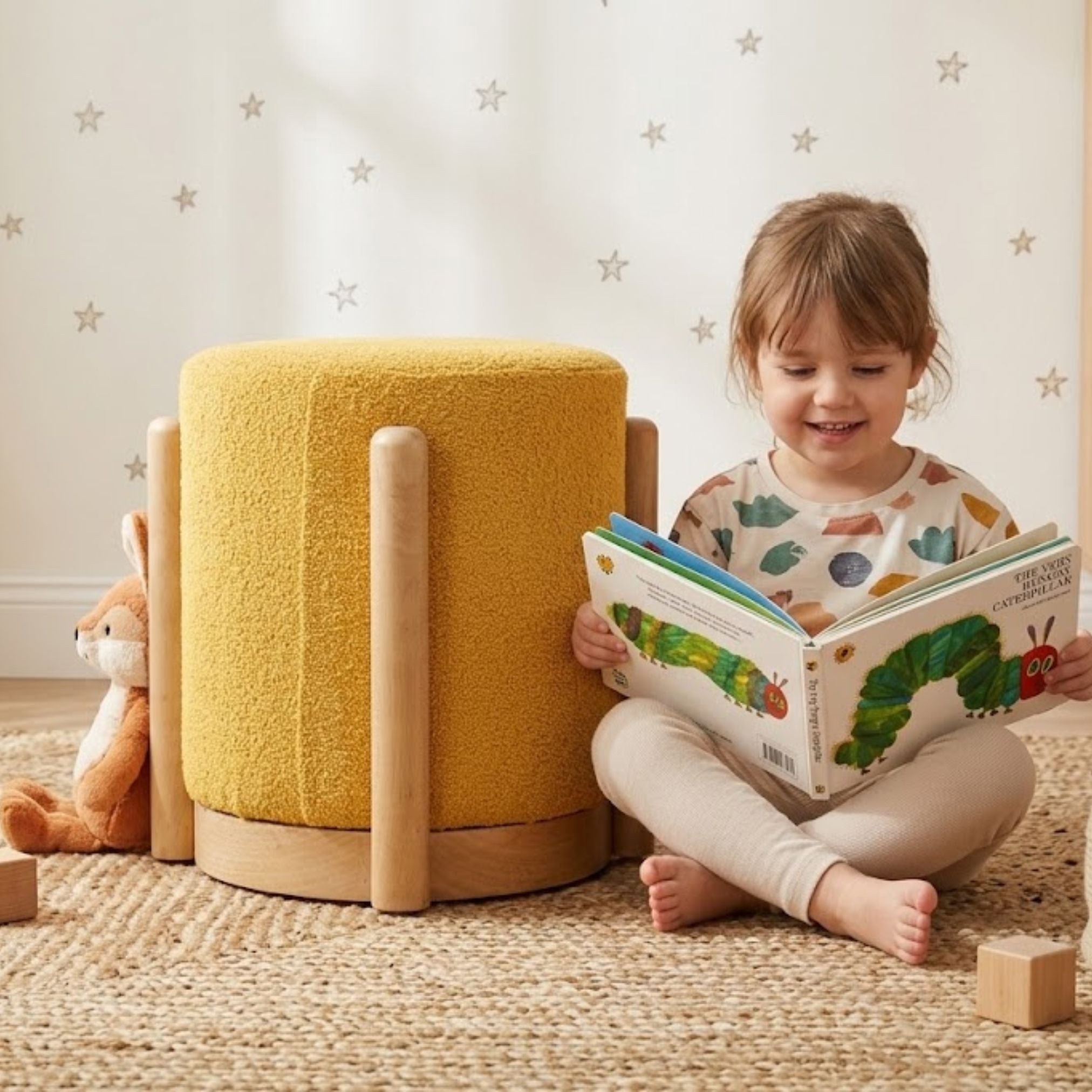 Piko upholstered wooden stool in yellow placed in a modern kids room with toys and soft decor